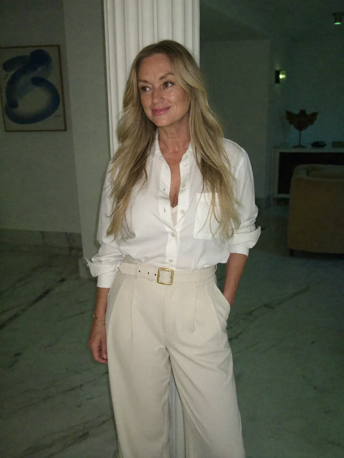 Paula Whiting, wearing a white shirt and cream trousers, standing with quiet confidence